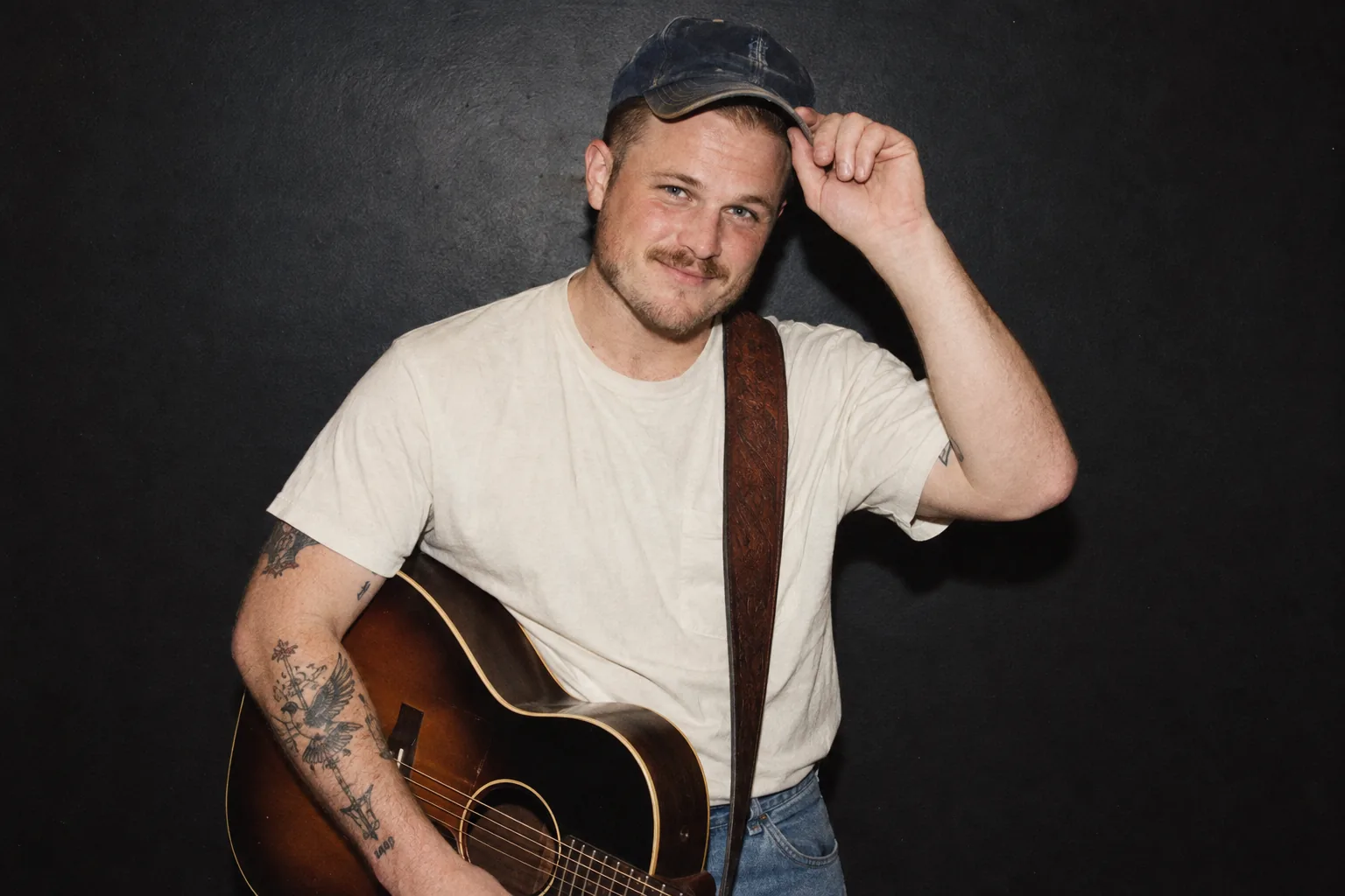 Zach Bryan smiling with his guitar